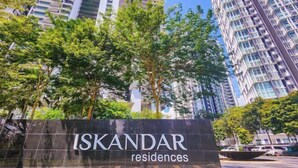 A sign for Iskandar Residences with a backdrop of high-rise buildings and trees.