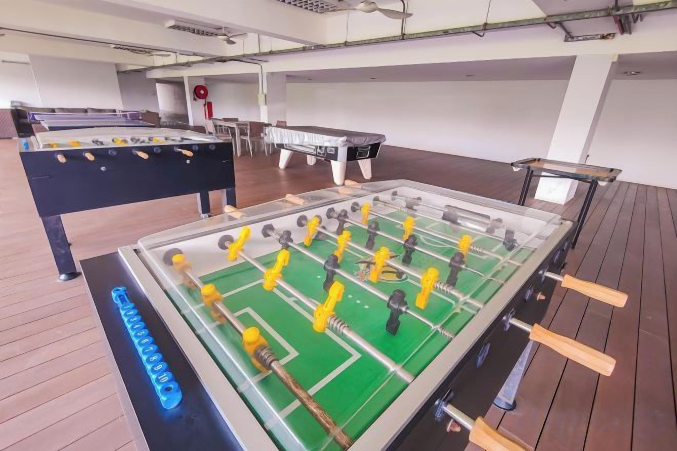 A room with two foosball tables, one with a green field and one with a black field.