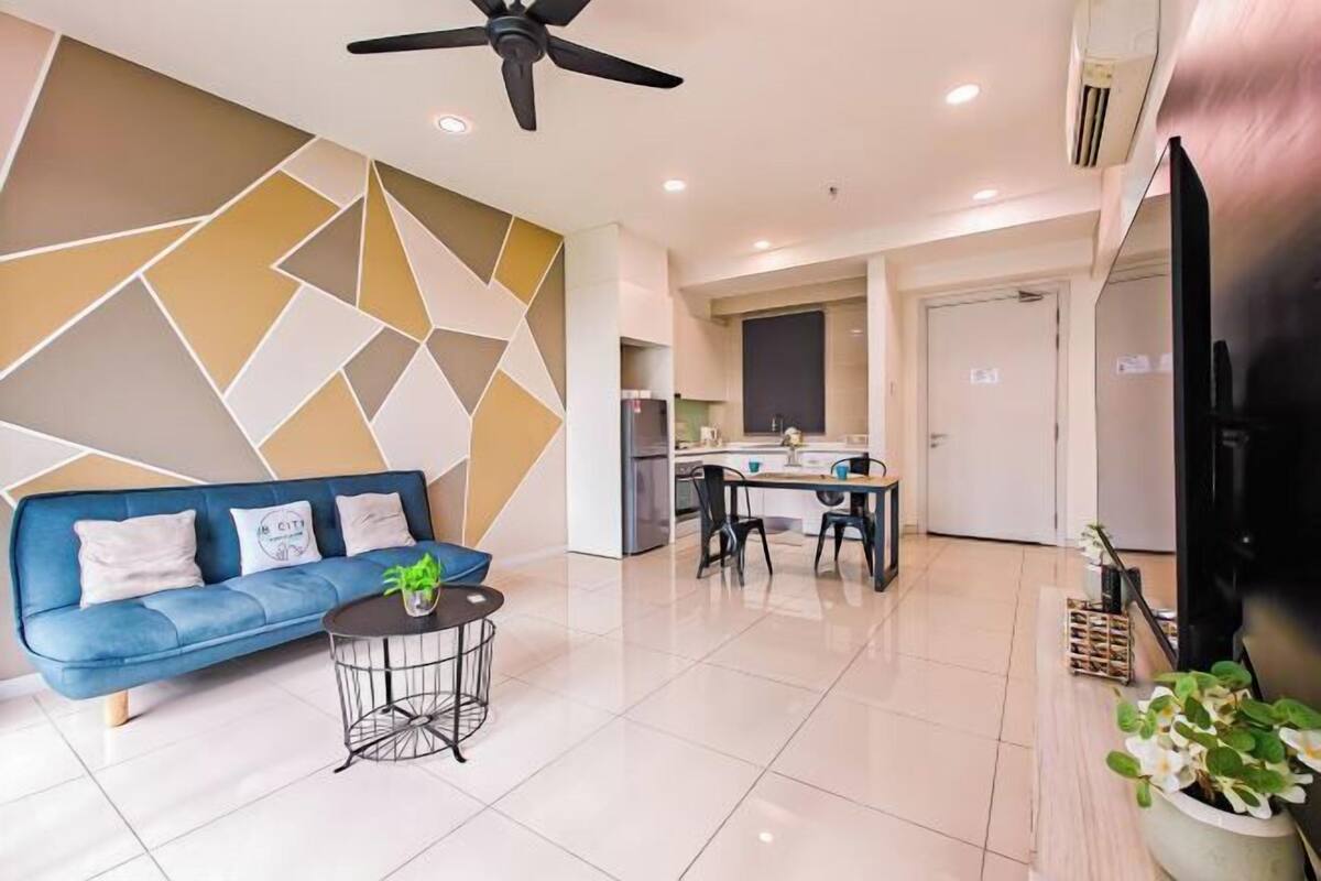 A modern living room with a blue sofa, a coffee table, and a kitchen in the background.
