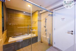A bathroom with a glass shower enclosure, a bathtub, and a white door with a sign.
