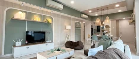 Una sala de estar moderna con un televisor de pantalla plana, un sofá, una mesa de centro y un comedor con sillas.