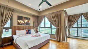 A spacious bedroom with a large bed, a ceiling fan, and large windows with curtains.