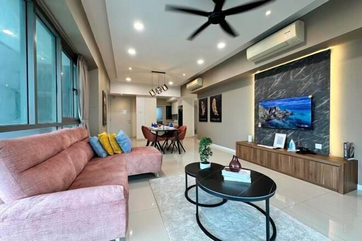 A modern living room with a sofa, coffee table, and a TV mounted on a marble wall.