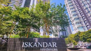 Un letrero que dice 'ISKANDAR residences' con vistas a edificios altos y árboles en el fondo.