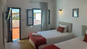 Ein Hotelzimmer mit zwei Betten, einem großen Fenster, einem Vorhang und Blick ins Freie.