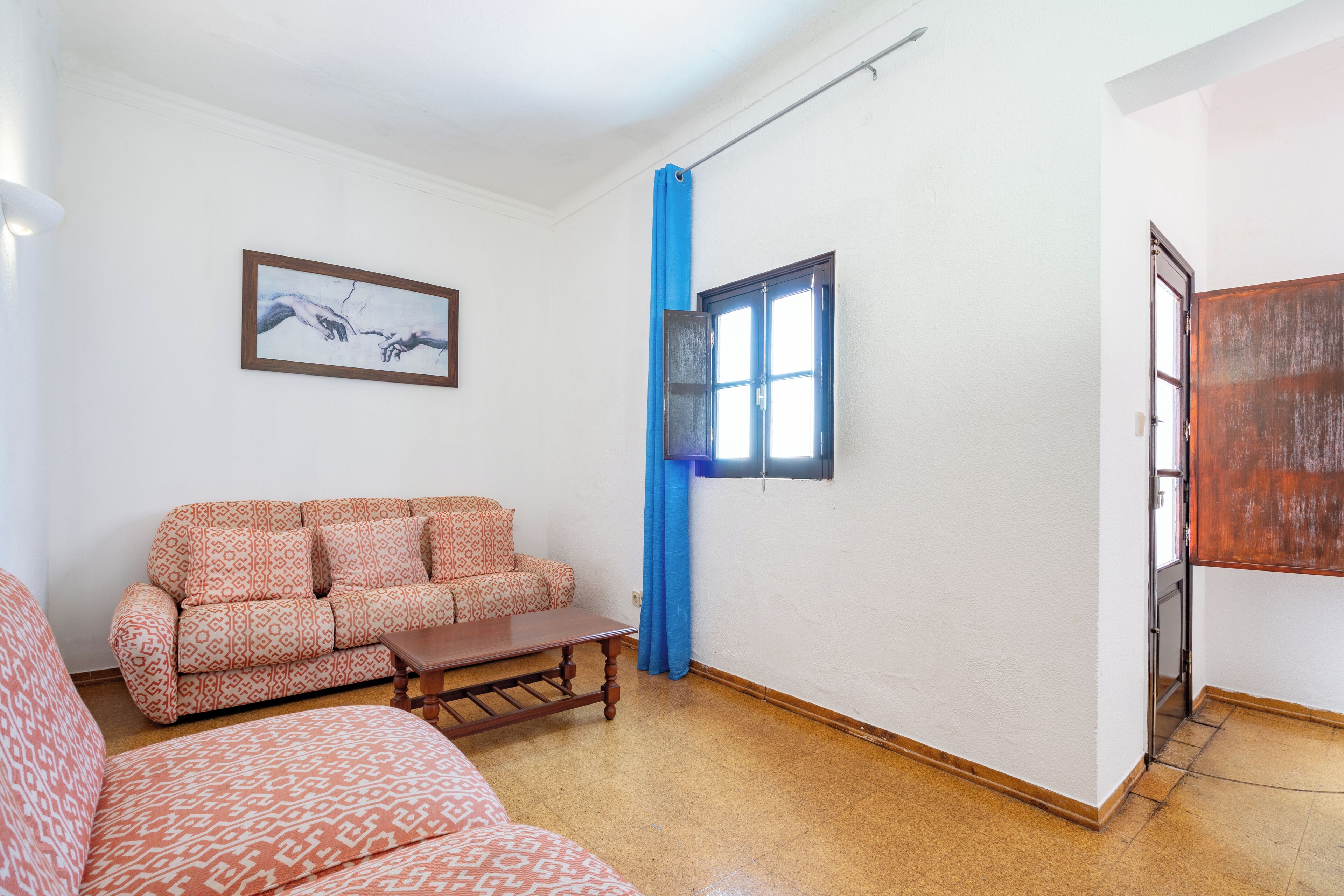 A living room with a patterned sofa, a wooden coffee table, and a painting on the wall.