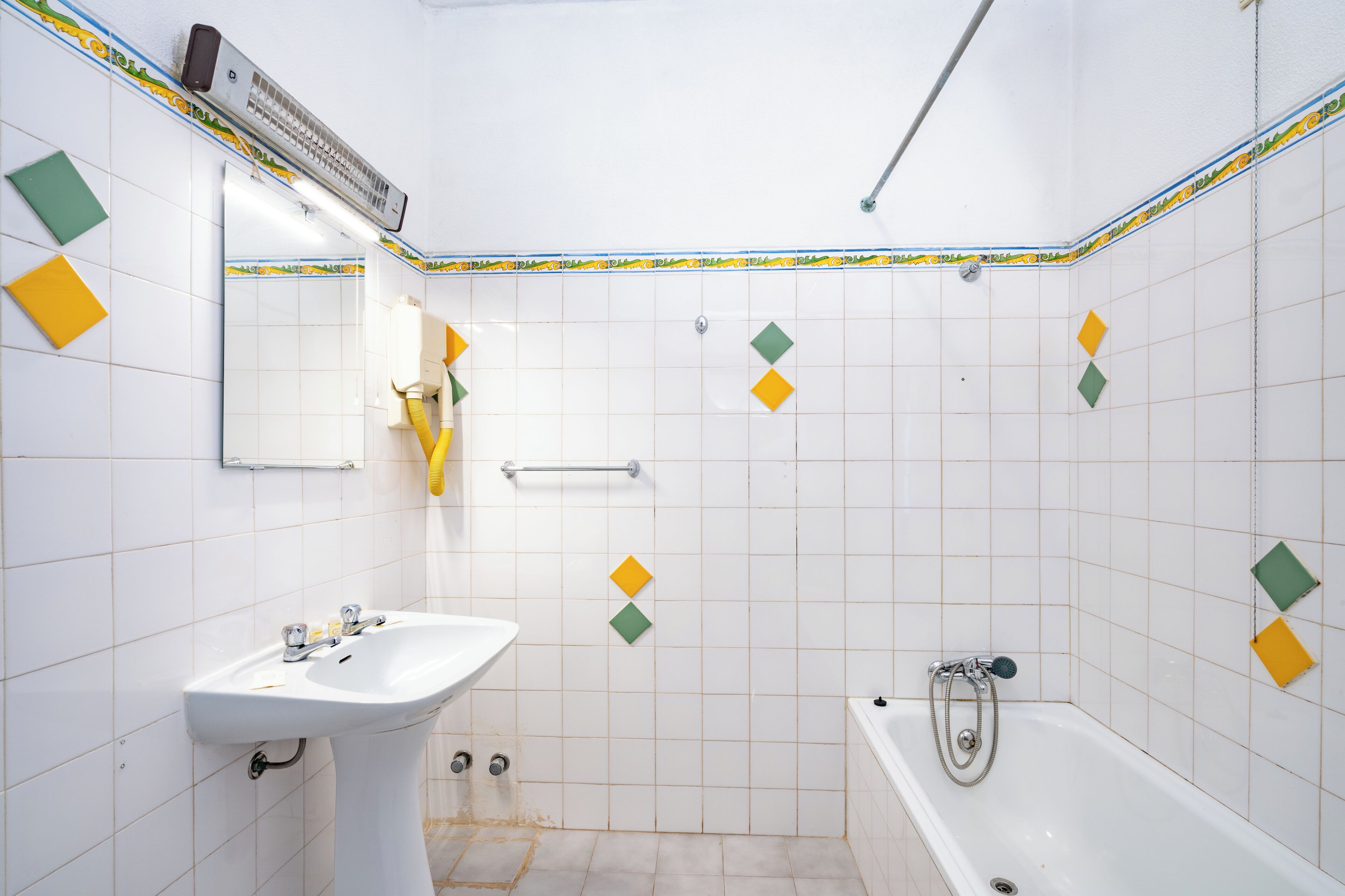 A bathroom with a sink, mirror, shower, and a towel rack.
