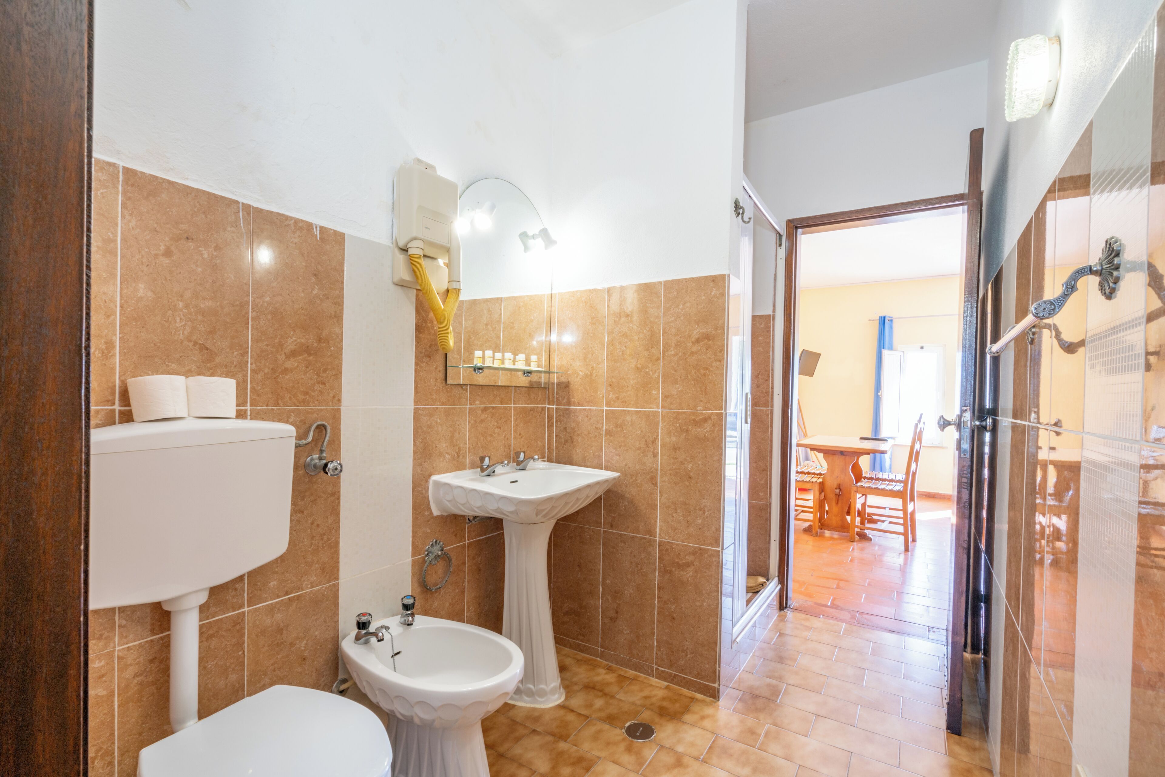 Un bagno con il water, un lavabo su piedistallo e una zona doccia.