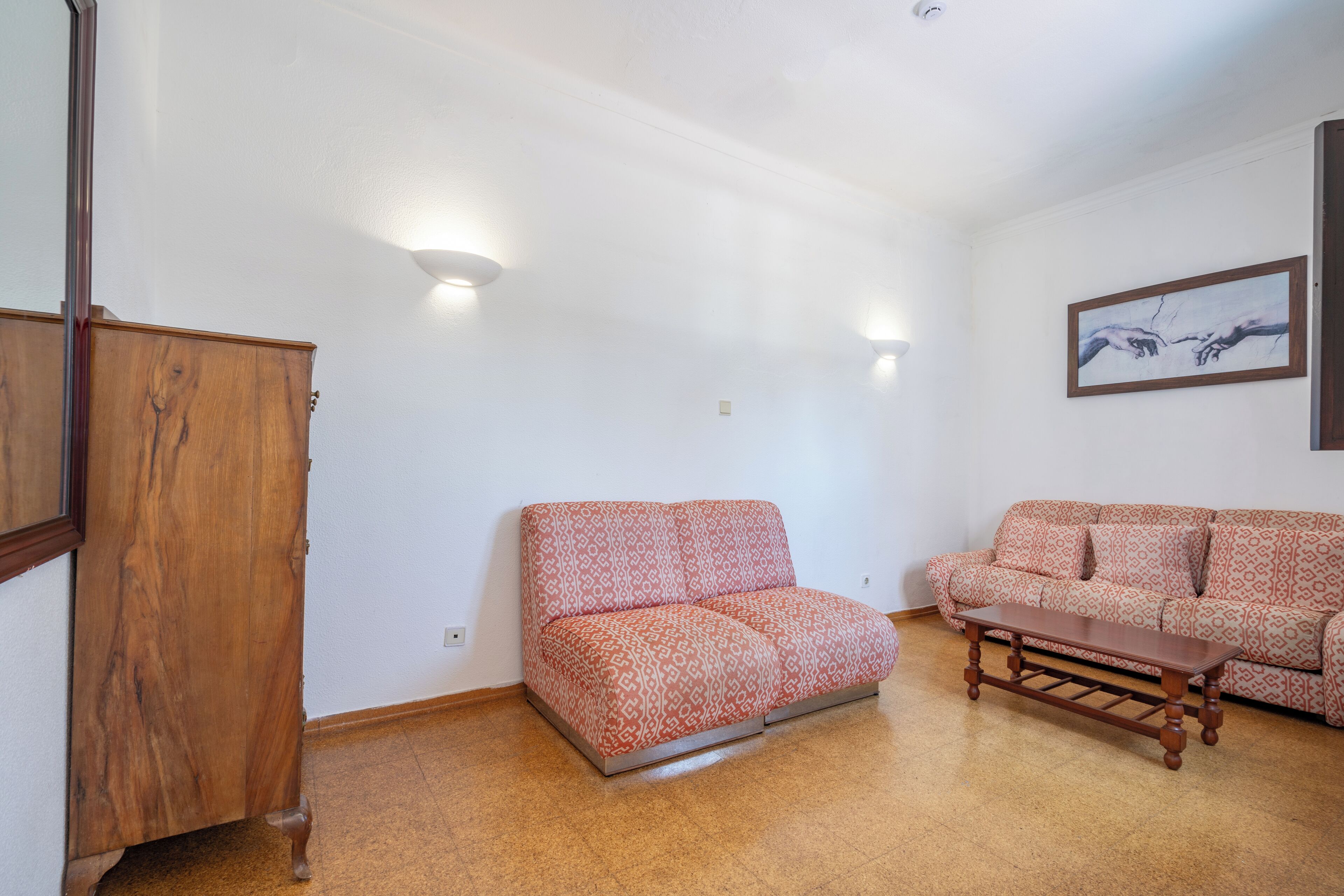 A living room with a wooden cabinet, a patterned sofa, and a wooden coffee table.