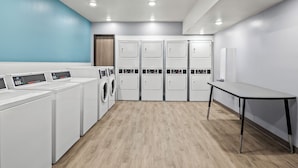Une buanderie équipée de plusieurs machines à laver, d’un étendoir et d’une table.
