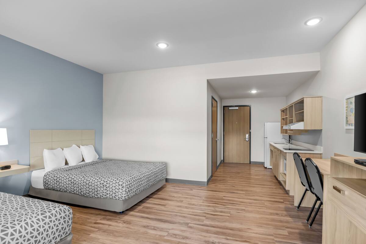 Een moderne hotelkamer met een groot bed, een bureau en een kitchenette.