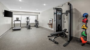 Un gimnasio con cintas de correr, máquinas de pesas y pelotas de ejercicio.