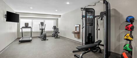 A gym with treadmills, a weight machine, and exercise balls.