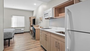 Une cuisine moderne avec des meubles en bois, un réfrigérateur blanc et un four à micro-ondes.