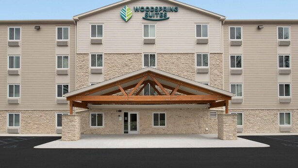 A hotel with a stone facade, multiple windows, and a covered entrance. - WoodSpring Suites Cleveland North (Cleveland)