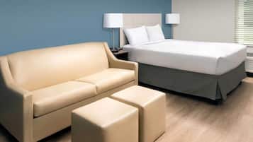 A hotel room with a bed, a sofa, and an ottoman.