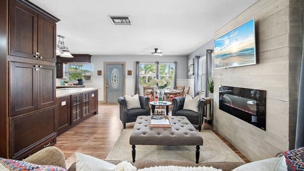 A spacious living area with a kitchen, dining area, and a fireplace. - The Club at Naples Park | Pool, Bocce & Putting Green (Naples)