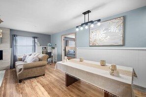 Ein Zimmer mit einer Couch, einem Tisch mit Tassen, einem Gemälde und einem Fenster mit Vorhängen.