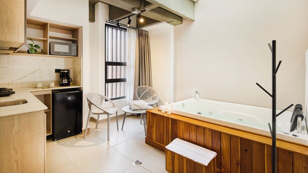 A modern bathroom with a freestanding bathtub, a sink, and a compact refrigerator. - Hotel Attic 33 (Medellín)