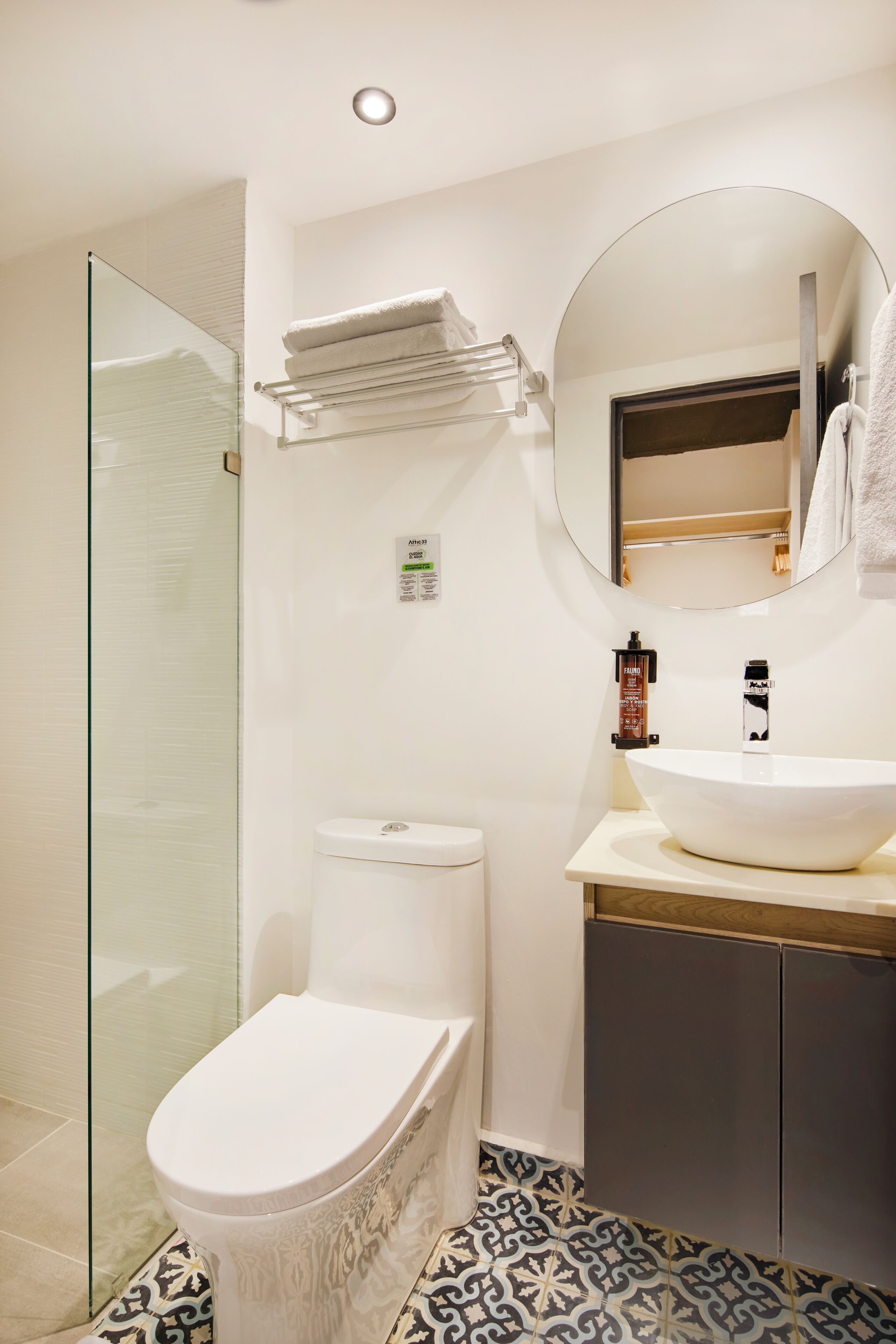 A bathroom with a glass shower enclosure, a toilet, a sink with a mirror, and a towel rack.