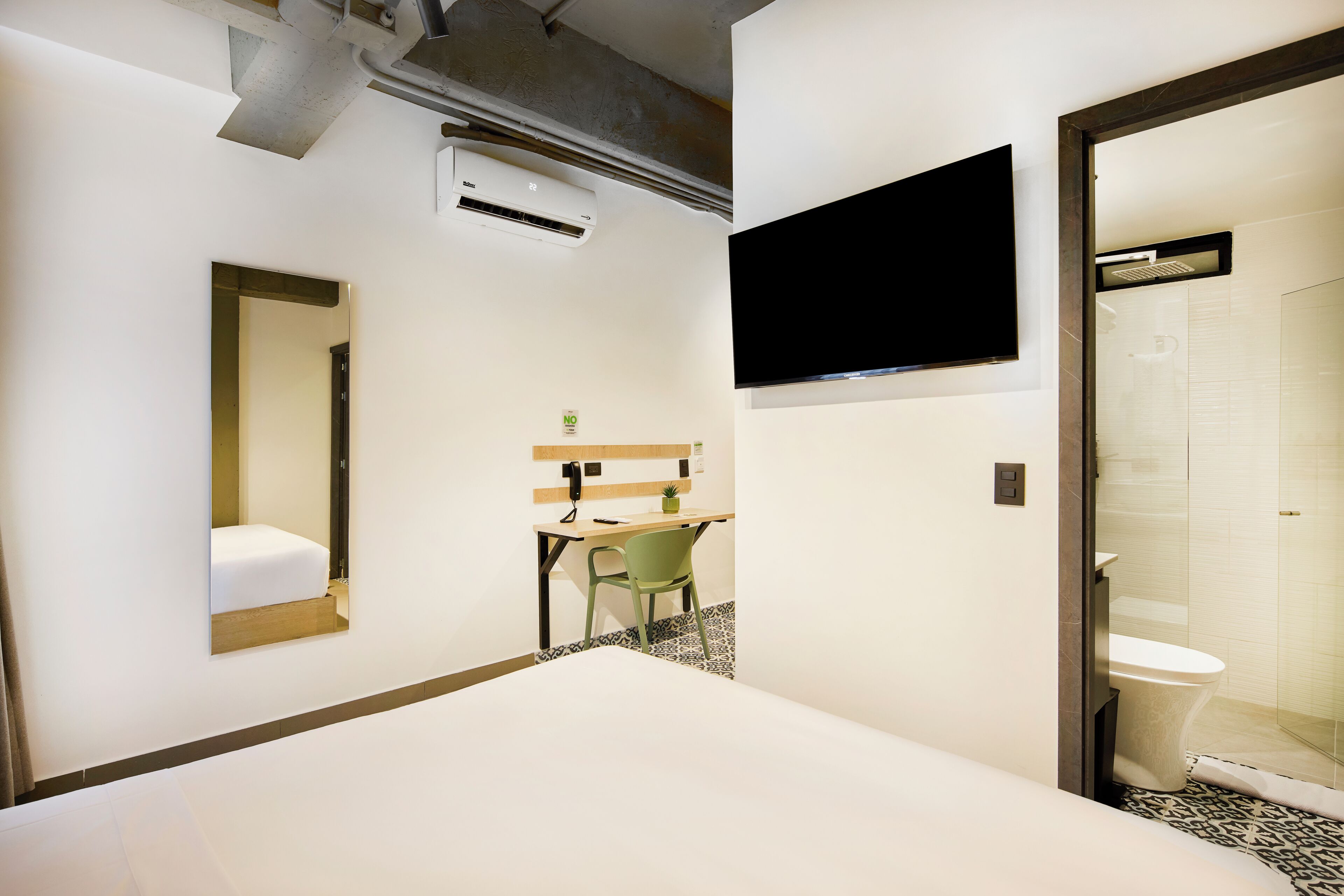 Une chambre d’hôtel équipée d’un lit, d’un bureau, d’une chaise, d’une télévision et d’un espace douche.