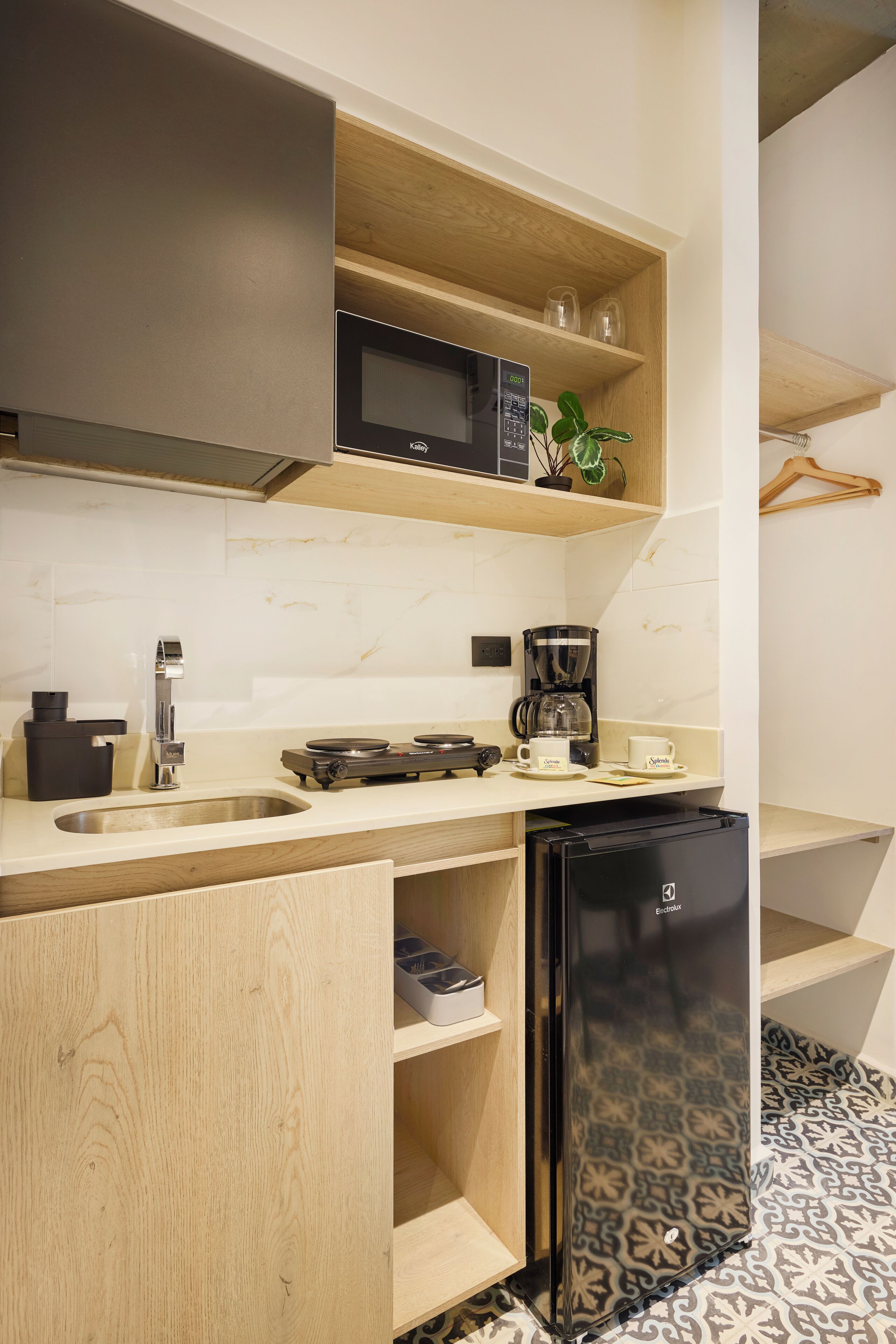 Eine kleine Küche mit Mikrowelle, Kaffeemaschine und Kühlschrank.