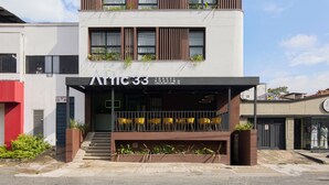 A modern multi-story building with balconies, a covered entrance, and outdoor seating. - Hotel Attic 33 (Medellín)