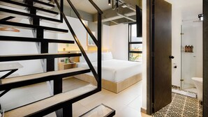 A modern bedroom with a wooden staircase, a bed, and a bathroom with a shower and toilet. - Hotel Attic 33 (Medellín)