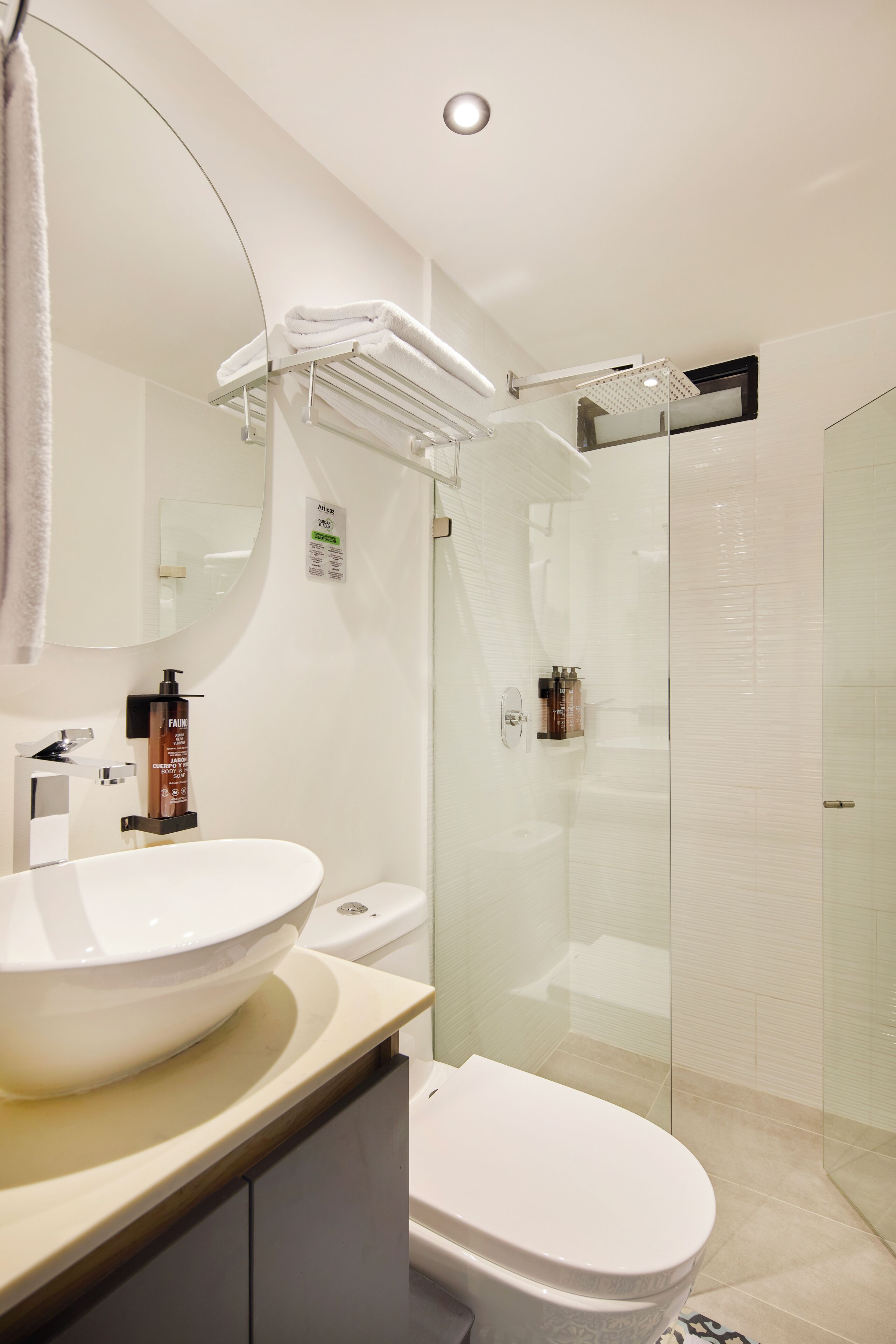 Um banheiro moderno com uma pia grande e branca, vaso sanitário, box de vidro para chuveiro e porta-toalhas.