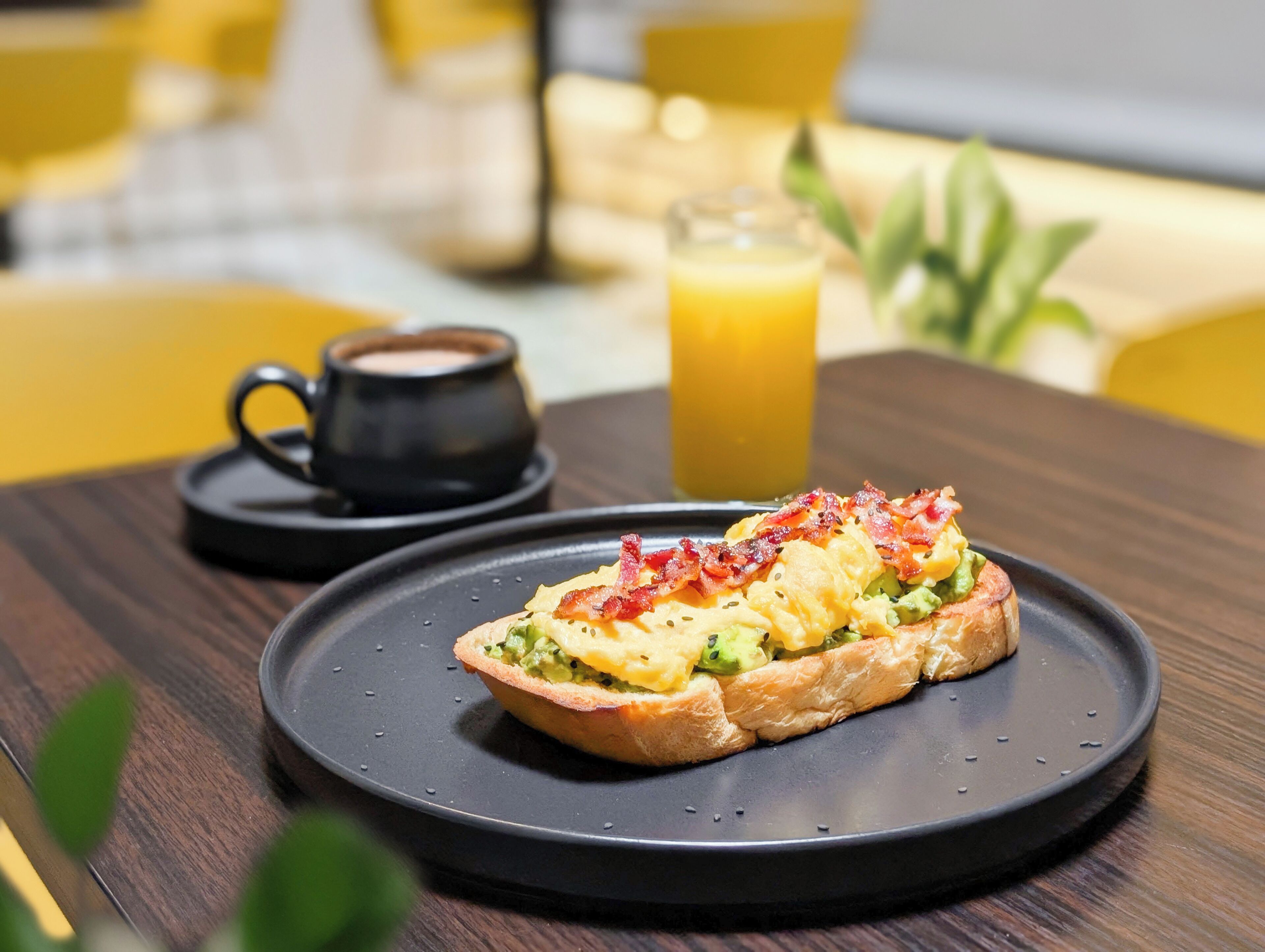 A breakfast setting with a plate of food, a cup of coffee, and a glass of orange juice on a wooden table.