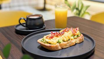 A breakfast setting with a plate of food, a cup of coffee, and a glass of orange juice on a wooden table.
