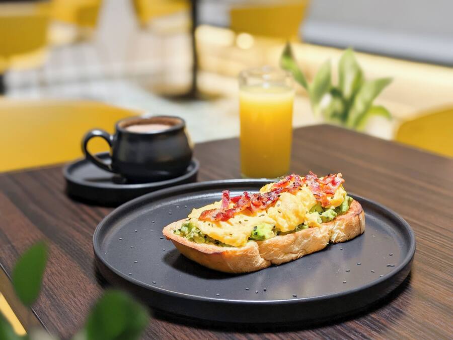 A breakfast setting with a plate of food, a cup of coffee, and a glass of orange juice on a wooden table.