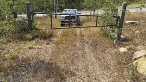 A vehicle approaching a gated entrance in a wooded area.