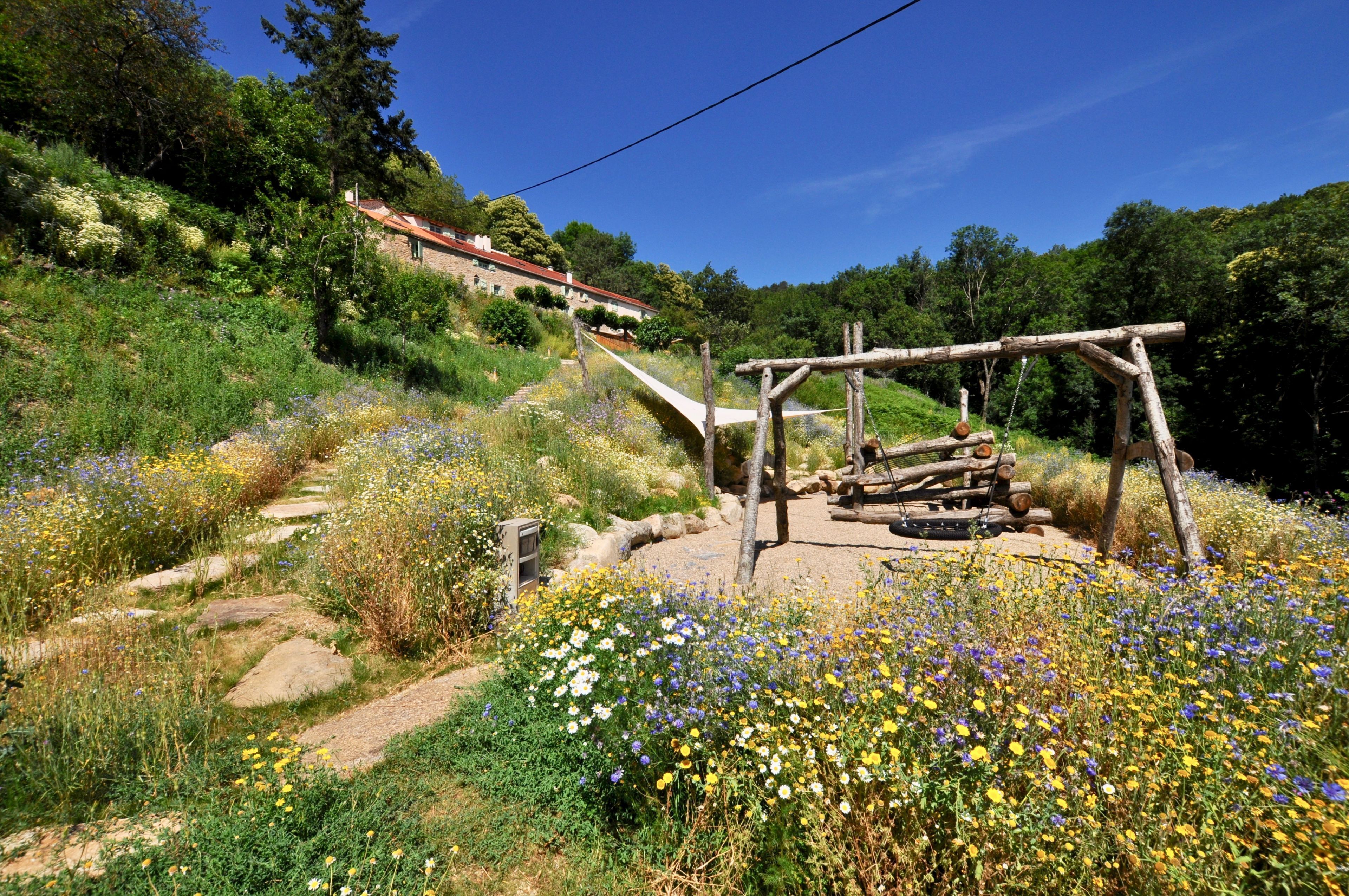 A garden with a wooden swing set and a stone pathway.