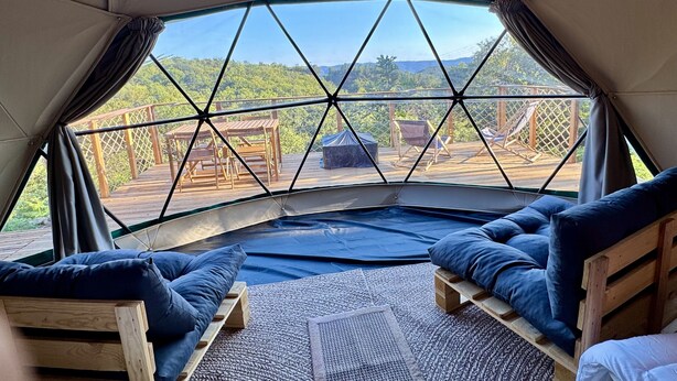 A cozy tent with a view of a wooden deck and greenery. Inside, there are two wooden beds with blue bedding. - Bambou Dome - Cosy dome with panoramic mountain views, surrounded by beautiful nature (Riols)