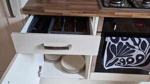 A kitchen with a white cabinet, a wooden countertop, a stove, and a drawer with plates. - Walk to East Croydon Station, 15 min direct train to Gatwick and Central London (Greater London)