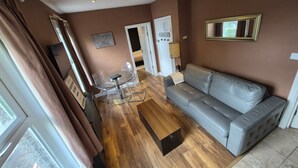 A living room with a grey sofa, a glass coffee table, and a dining area with clear chairs and a small table. - Walk to East Croydon Station, 15 min direct train to Gatwick and Central London (Greater London)