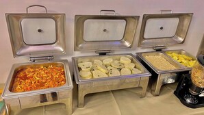 A buffet with various food items including a dish with vegetables, a tray of white cubes, and a container of yellow fruit. - Monabliss Hotel and Suites  (Abakaliki)