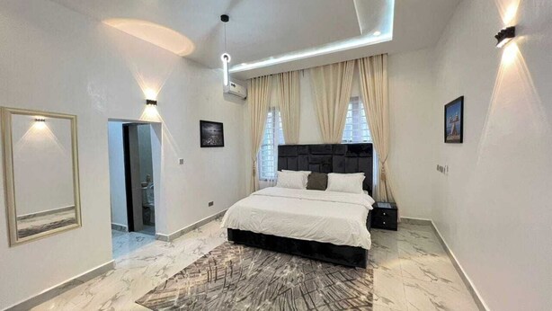 A modern bedroom with a large bed, a marble floor, and a ceiling light fixture. - Monabliss Hotel and Suites  (Abakaliki)