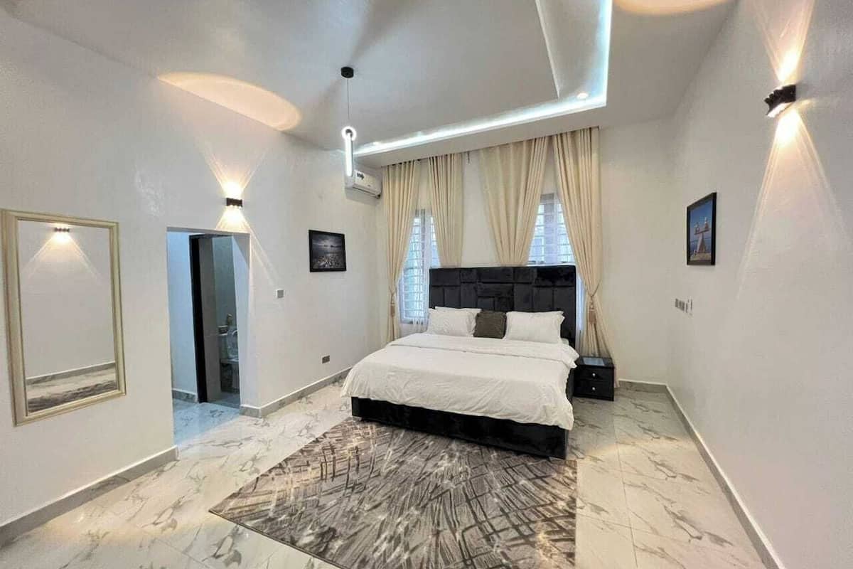 A modern bedroom with a large bed, a marble floor, and a ceiling light fixture.