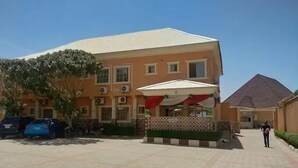 A building with a tiled roof, a covered outdoor seating area, and a paved courtyard. - Monabliss Hotel and Suites  (Abakaliki)