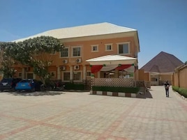 Un edificio con techo de tejas, un espacio de estar techado al aire libre y un patio empedrado.