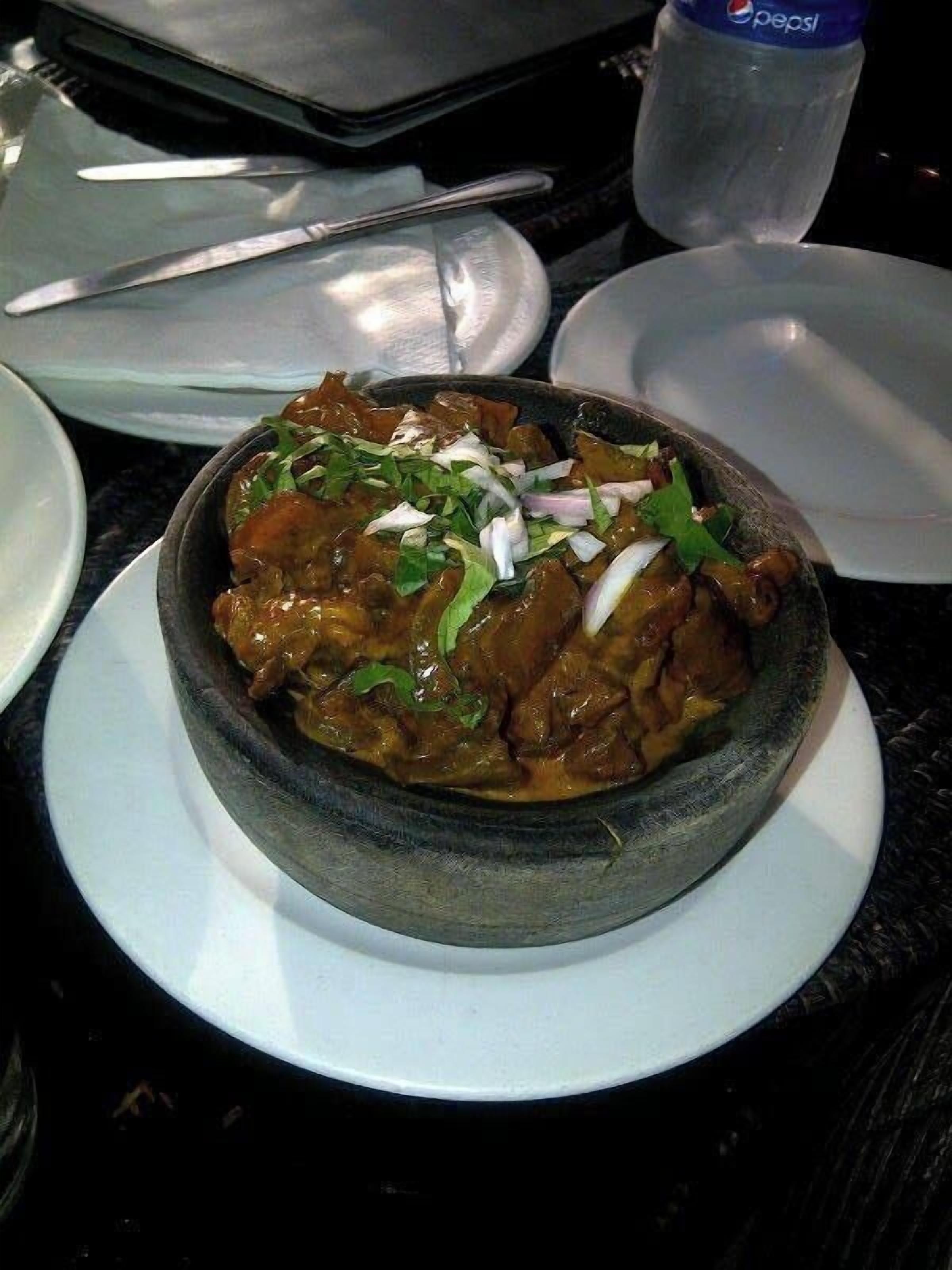 Un plato blanco con curry, cebollas y hierbas verdes.