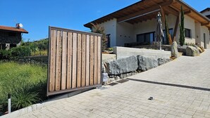 Una casa moderna con facciata in pietra, un patio in legno e un vialetto in pietra che conduce all'ingresso.
