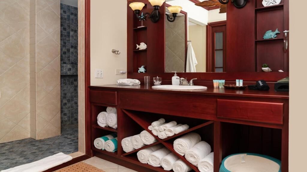 Un bagno con un mobile bagno in legno, un ampio specchio e mensole con asciugamani.