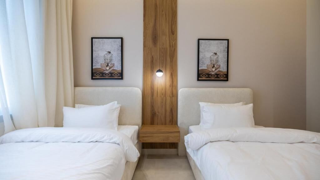 A hotel room with two single beds, a wooden accent wall, and two framed artworks above the beds.