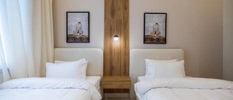 A hotel room with two single beds, a wooden accent wall, and two framed artworks above the beds.