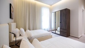 A modern hotel room with two beds, a large mirror, and a wardrobe.