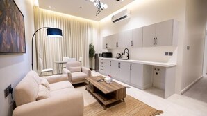 A modern living room with a sofa, coffee table, and a kitchen area with cabinets and appliances. - Super Luxury two Bedroom Al Narjis (Riyadh)