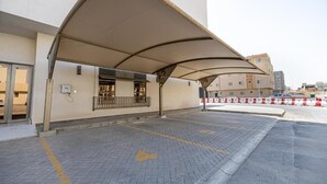 A covered outdoor area with a paved walkway, a building entrance, and a security barrier. - Super Luxury two Bedroom Al Narjis (Riyadh)